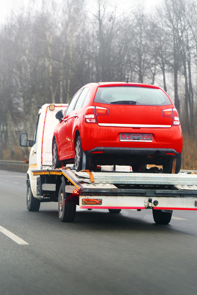 Autoturism tractat pe platformă, în drum spre service